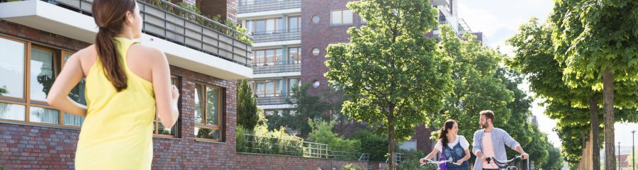 Couple pushing bicycles and woman jogging in a newly built housing estate