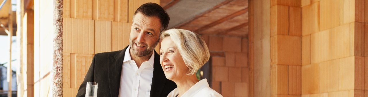 Couple inside building shell surrounded by bare brickwork celebrating their new home