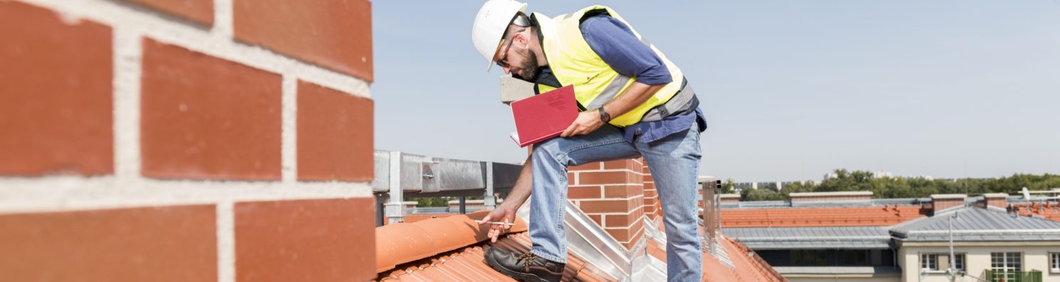 Urban roofer product manager checking ridge system wearing safety jacket and hard hat in an urban location