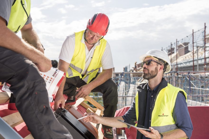 Product manager explaining product advantages to urban roofers wearing safety jackets and hard hats