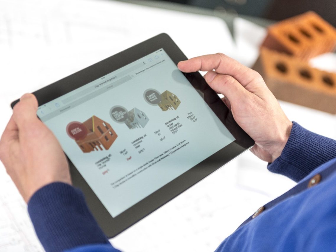 Hands holding tablet showing a comparison of building types