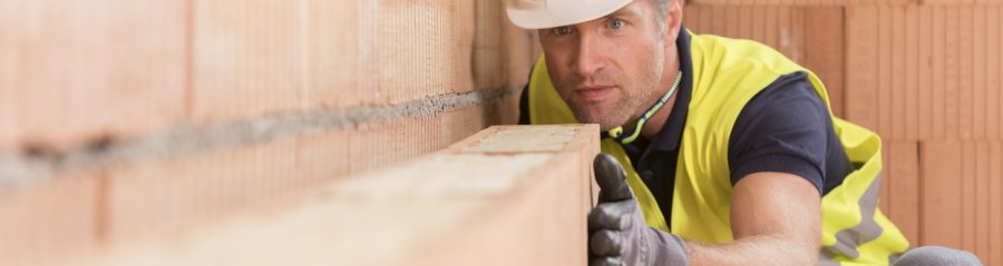 Construction worker checking alignment of mineral-wool filled clay block