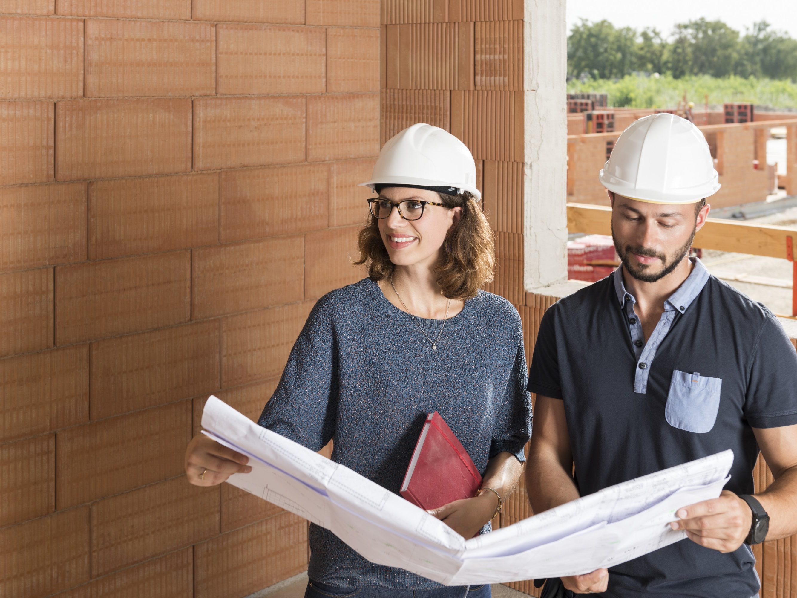 Male and female building professionals with technical drawing in new built construction