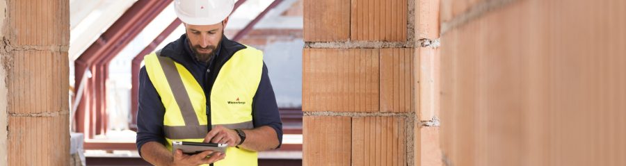 Product manager standing in attic under renovation checking tablet