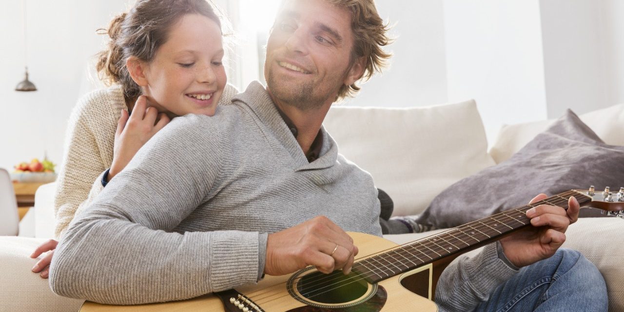 Girl listens to man playing guitar